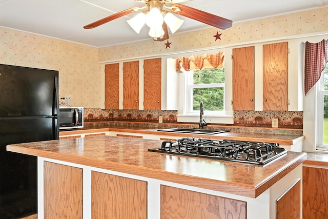 23 W St, Benton, ME 04901 - kitchen with freestanding refrigerator, gas stovetop, a ceiling fan, wallpapered walls, and decorative backsplash