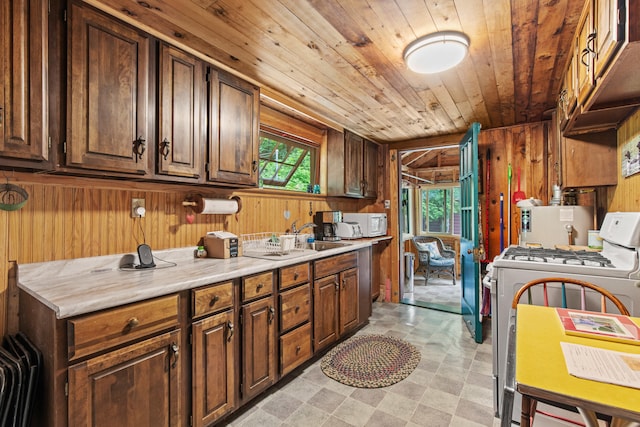 199 Peace Pipe Dr, Litchfield, ME 04350 - kitchen with white appliances, wooden walls, wood ceiling, light countertops, and light floors