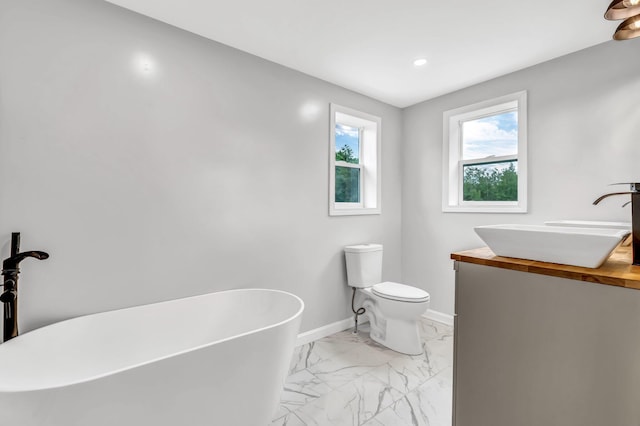 985 Main Rd, Eddington, ME 04428 - bathroom featuring a freestanding bath, marble look tiles, vanity, and recessed lighting