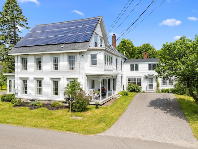 50-52 Mechanic St, Rockland, ME 04841 - view of front of property featuring a chimney, roof mounted solar panels, a front lawn, asphalt driveway, and roof with shingles