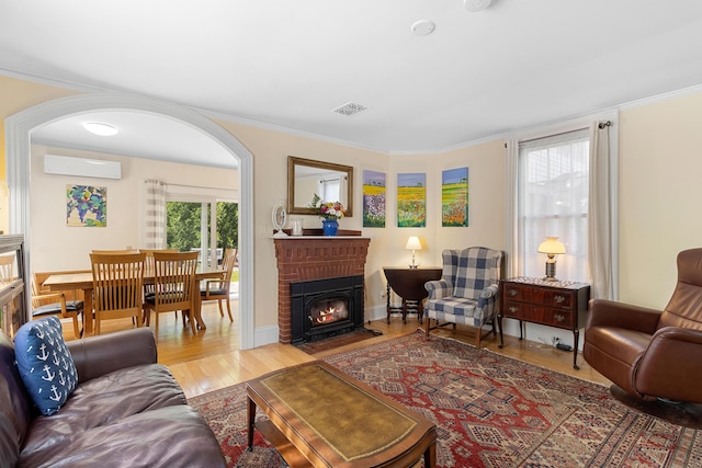 50-52 Mechanic St, Rockland, ME 04841 - living area featuring a wall mounted AC, a fireplace, wood finished floors, ornamental molding, and arched walkways