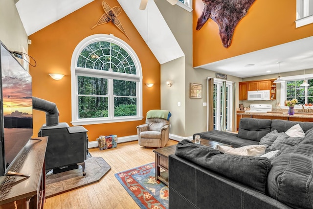 2 Falling Pines Ln, Readfield, ME 04355 - living area featuring a wood stove, high vaulted ceiling, light wood-type flooring, and a baseboard radiator