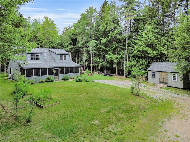 134 Powers Drive Ln, Orland, ME 04472 - view of green lawn with a sunroom, an outbuilding, driveway, and a wooded view