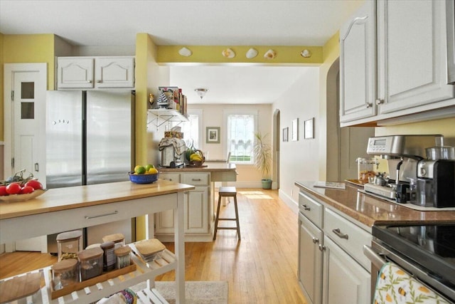 278 S Main St, Auburn, ME 04210 - kitchen featuring light wood-style floors, freestanding refrigerator, arched walkways, and white cabinets