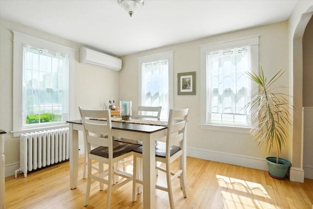 278 S Main St, Auburn, ME 04210 - dining space featuring radiator, a wall mounted air conditioner, plenty of natural light, and wood finished floors