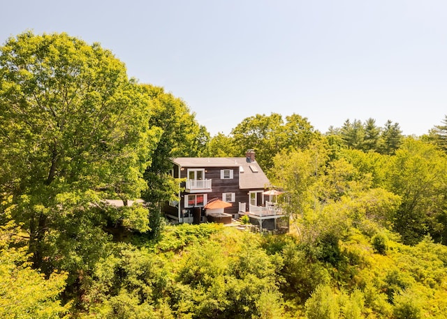 103 Hardscrabble Rd, Hollis, ME 04042 - back of property featuring a chimney, a balcony, a deck, and a forest view