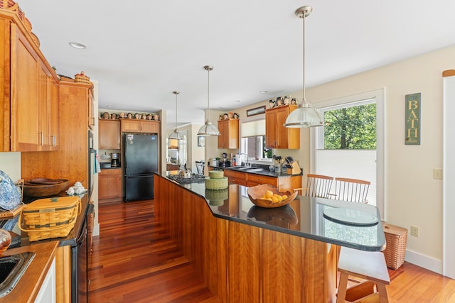 250 Mere Point Rd, Brunswick, ME 04011 - kitchen with freestanding refrigerator, a center island, wood finished floors, dark countertops, and brown cabinets