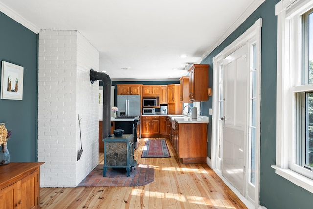 253 Quaker Meeting House Rd, Durham, ME 04222 - kitchen featuring appliances with stainless steel finishes, a wood stove, light wood-style flooring, healthy amount of natural light, and crown molding