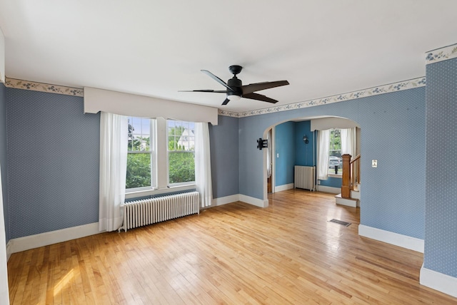 15 Huston Ave, Auburn, ME 04210 - spare room with radiator, arched walkways, wallpapered walls, and light wood-type flooring