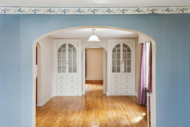 15 Huston Ave, Auburn, ME 04210 - empty room with light wood finished floors, arched walkways, and wallpapered walls