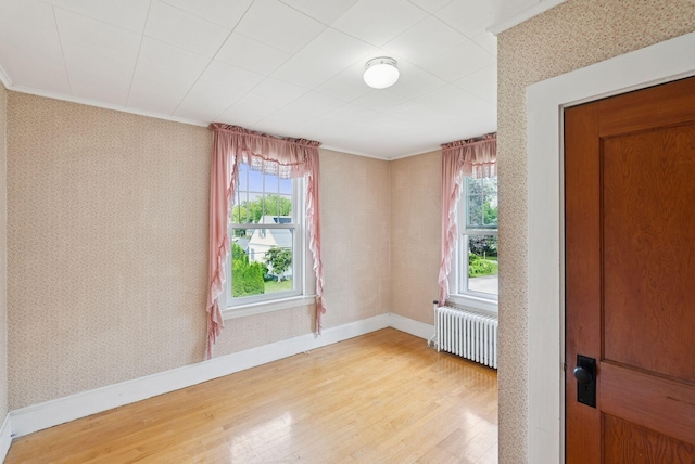 15 Huston Ave, Auburn, ME 04210 - spare room with radiator heating unit, light wood finished floors, wallpapered walls, and ornamental molding