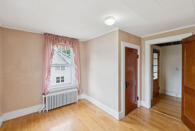 15 Huston Ave, Auburn, ME 04210 - spare room with radiator heating unit, ornamental molding, light wood-style flooring, and wallpapered walls