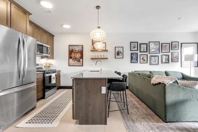 218 Washington Ave Unit 408, Portland, ME 04101 - kitchen with stainless steel appliances, open floor plan, a breakfast bar, an island with sink, and pendant lighting