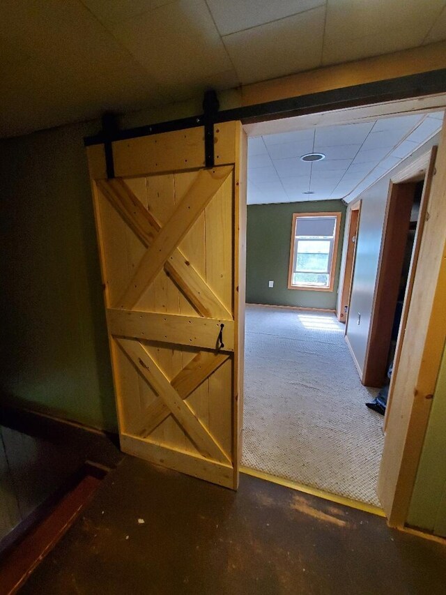523 Exeter Rd, Corinth, ME 04427 - hallway featuring a barn door, a drop ceiling, and carpet flooring