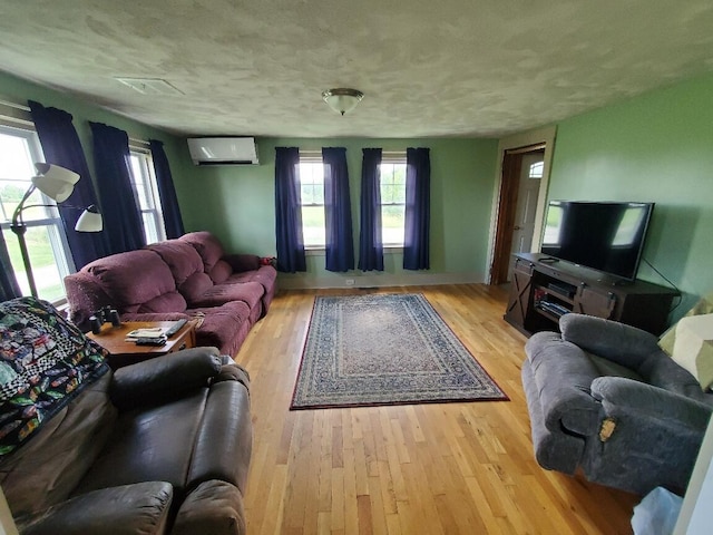 523 Exeter Rd, Corinth, ME 04427 - living area featuring a wall mounted air conditioner, wood finished floors, healthy amount of natural light, and a textured ceiling