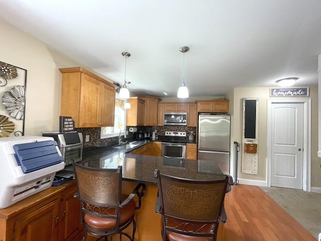 28 Kayla Way, Gorham, ME 04038 - kitchen featuring stainless steel appliances, decorative backsplash, decorative light fixtures, dark stone countertops, and wood finished floors
