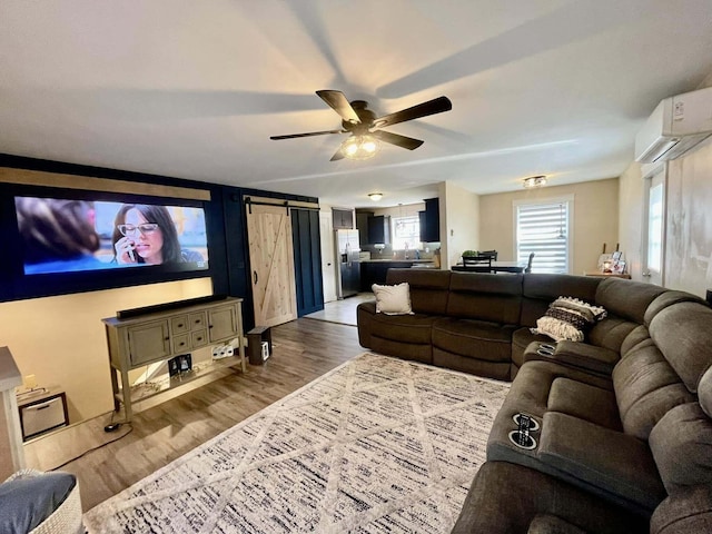 28 Kayla Way, Gorham, ME 04038 - living room featuring a wall mounted AC, wood finished floors, a barn door, and a ceiling fan