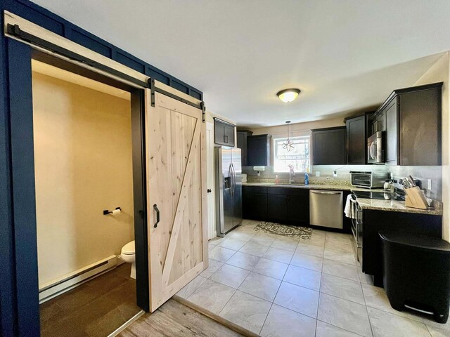 28 Kayla Way, Gorham, ME 04038 - kitchen with appliances with stainless steel finishes, baseboard heating, a barn door, light stone counters, and dark cabinets
