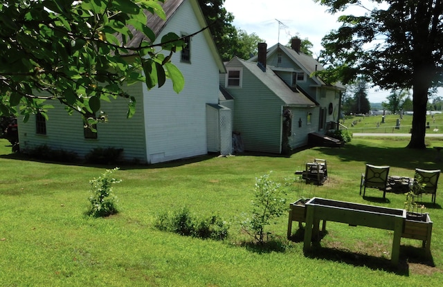 10 Liberty St, Dexter, ME 04930 - view of side of property featuring an outdoor fire pit, a chimney, and a yard