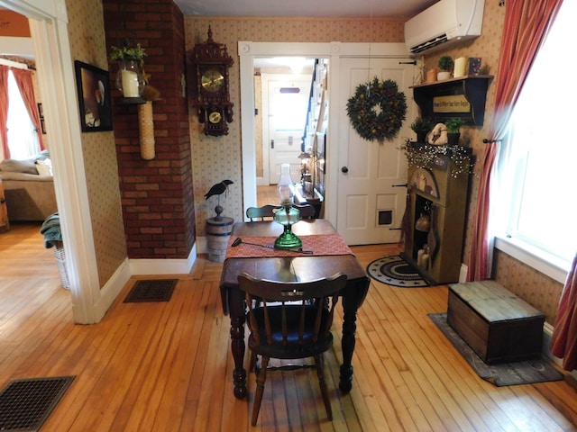 10 Liberty St, Dexter, ME 04930 - dining area featuring a wall mounted air conditioner, wallpapered walls, light wood-style flooring, and a fireplace