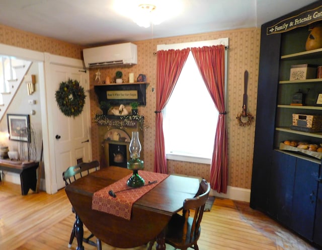 10 Liberty St, Dexter, ME 04930 - dining room featuring an AC wall unit, wallpapered walls, wood finished floors, and stairway
