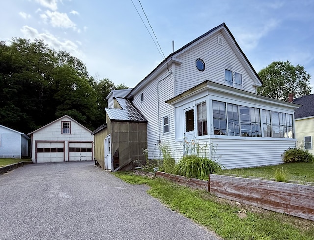322 Katahdin Ave, Millinocket, ME 04462 - view of side of home featuring a garage, an outdoor structure, and a sunroom