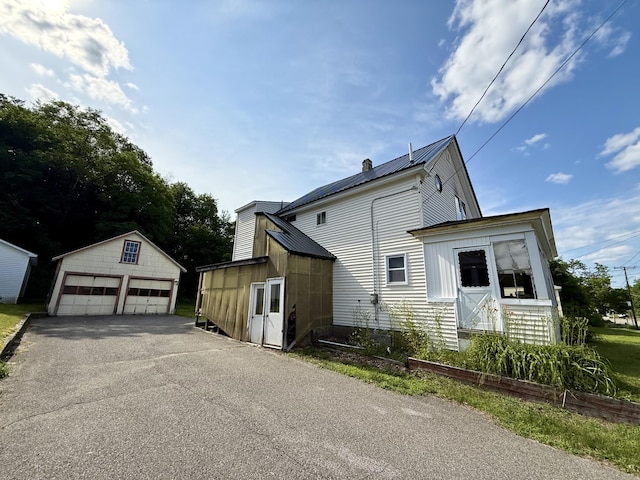 322 Katahdin Ave, Millinocket, ME 04462 - view of side of property with a detached garage, an outbuilding, a metal roof, and a chimney