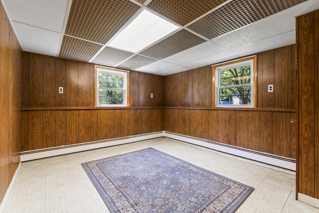 232 Augusta Rd, Topsham, ME 04086 - empty room featuring wood walls, tile patterned floors, a baseboard heating unit, and a drop ceiling