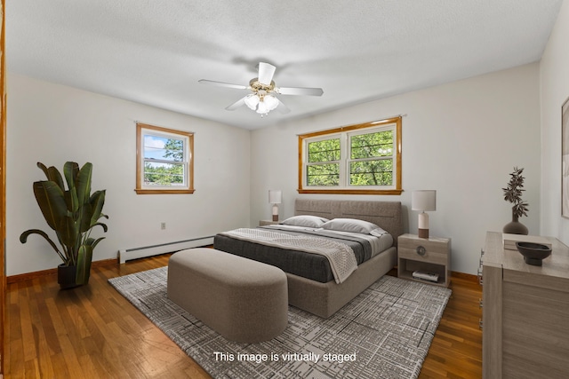232 Augusta Rd, Topsham, ME 04086 - bedroom featuring a baseboard heating unit, multiple windows, dark wood-style flooring, and a ceiling fan