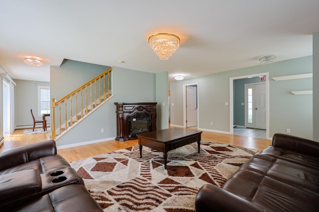 18 Wilson Dr, Westbrook, ME 04092 - living room with a baseboard radiator, light wood-style flooring, stairway, a glass covered fireplace, and a chandelier