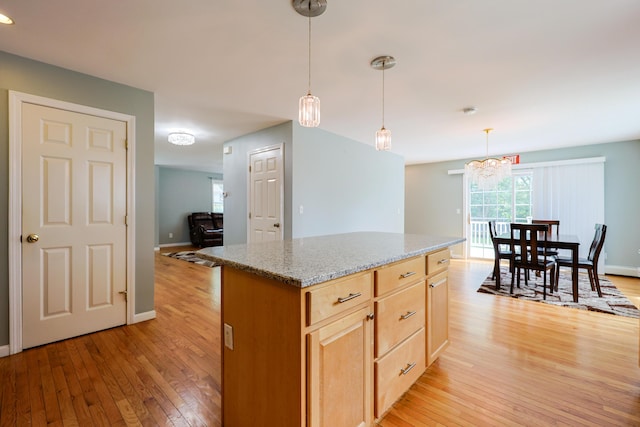 18 Wilson Dr, Westbrook, ME 04092 - kitchen featuring light wood-style flooring, light brown cabinetry, light stone counters, hanging light fixtures, and a kitchen island