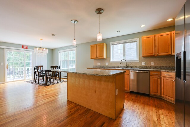 18 Wilson Dr, Westbrook, ME 04092 - kitchen with appliances with stainless steel finishes, hardwood / wood-style floors, a kitchen island, tasteful backsplash, and dark stone counters