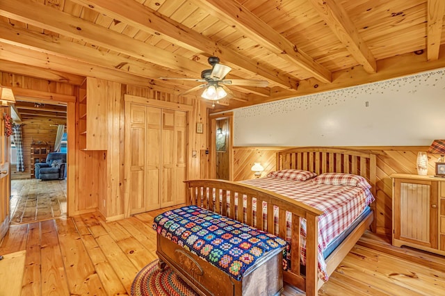 642 Mingo Loop Rd, Rangeley, ME 04970 - bedroom with wood walls, light wood-type flooring, a wood ceiling with exposed beams, and a closet