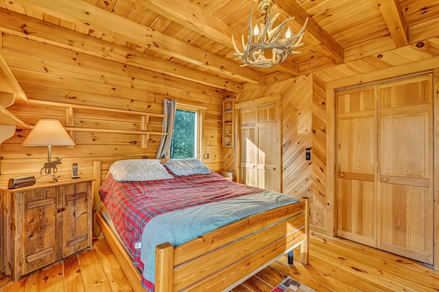 642 Mingo Loop Rd, Rangeley, ME 04970 - bedroom featuring a chandelier, light wood-style floors, a wood ceiling with exposed beams, and wooden walls