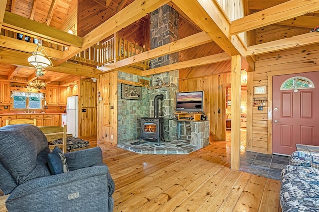 642 Mingo Loop Rd, Rangeley, ME 04970 - living area with wooden walls, hardwood / wood-style floors, beamed ceiling, a wood stove, and a towering ceiling