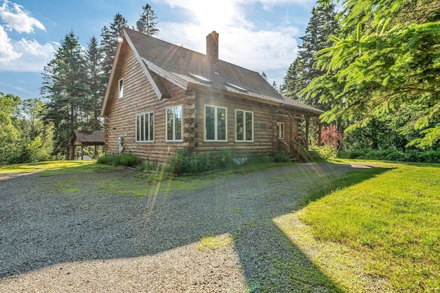 642 Mingo Loop Rd, Rangeley, ME 04970 - view of home's exterior featuring a chimney, log siding, a yard, and gravel driveway