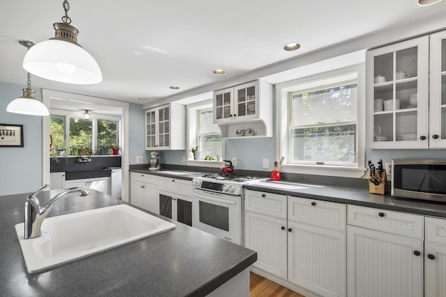 15 Winter St, Topsham, ME 04086 - kitchen featuring white range with gas cooktop, stainless steel microwave, dark countertops, pendant lighting, and white cabinetry