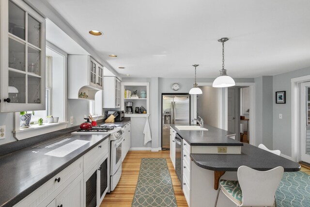 15 Winter St, Topsham, ME 04086 - kitchen featuring stainless steel appliances, light wood finished floors, dark countertops, a kitchen breakfast bar, and an island with sink
