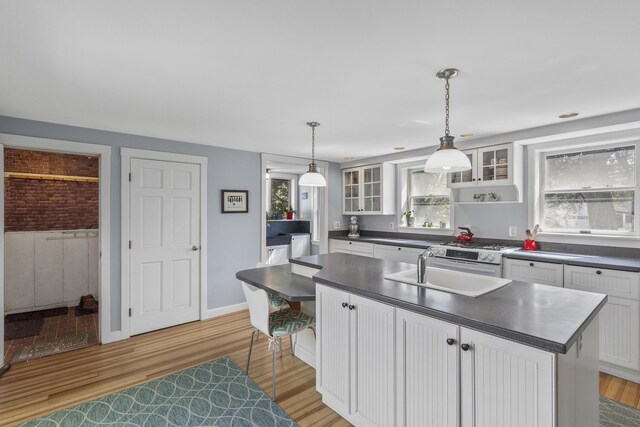 15 Winter St, Topsham, ME 04086 - kitchen with dark countertops, light wood-type flooring, glass insert cabinets, and white cabinetry