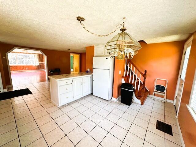 1039 Belfast Rd, Knox, ME 04986 - kitchen with freestanding refrigerator, a textured ceiling, a peninsula, a chandelier, and white cabinets