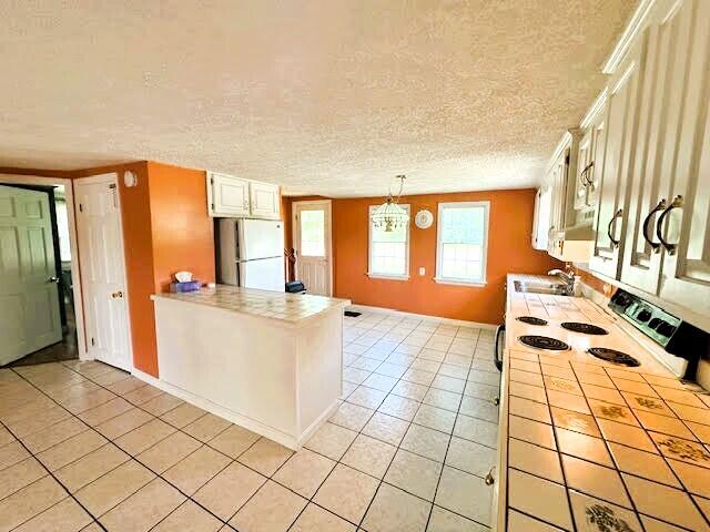 1039 Belfast Rd, Knox, ME 04986 - kitchen featuring tile countertops, white appliances, light tile patterned floors, white cabinets, and a textured ceiling