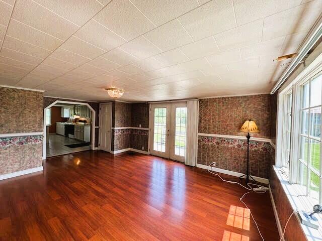 1039 Belfast Rd, Knox, ME 04986 - unfurnished living room with wood finished floors, french doors, and wallpapered walls