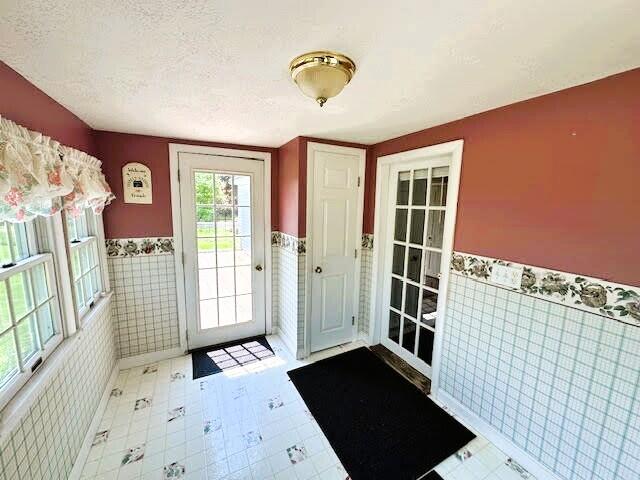 1039 Belfast Rd, Knox, ME 04986 - doorway featuring a wainscoted wall, tile walls, and a textured ceiling