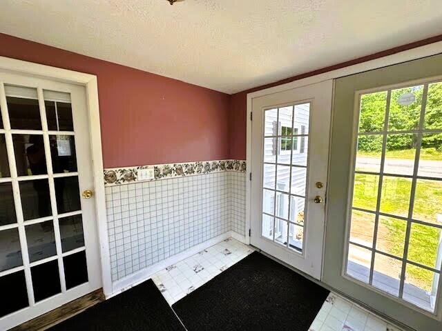 1039 Belfast Rd, Knox, ME 04986 - doorway with plenty of natural light, a wainscoted wall, a textured ceiling, and tile walls