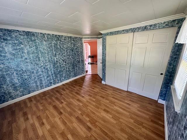 1039 Belfast Rd, Knox, ME 04986 - unfurnished bedroom featuring wood finished floors, ornamental molding, a closet, and wallpapered walls
