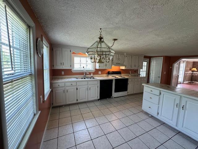 1039 Belfast Rd, Knox, ME 04986 - kitchen with electric stove, black dishwasher, a chandelier, light tile patterned floors, and white cabinets