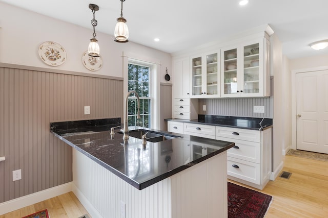 29 Folly Farm Rd, Lebanon, ME 04027 - kitchen with a peninsula, white cabinets, light wood-style flooring, glass insert cabinets, and dark stone counters