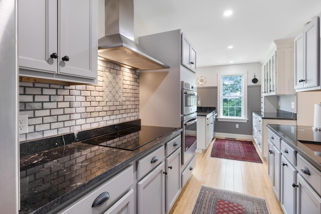 29 Folly Farm Rd, Lebanon, ME 04027 - kitchen featuring wall chimney range hood, black electric stovetop, light wood-type flooring, decorative backsplash, and stainless steel double oven