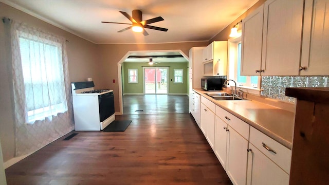 236 Birch St, Bangor, ME 04401 - kitchen with white gas range, a ceiling fan, stainless steel microwave, tasteful backsplash, and white cabinetry