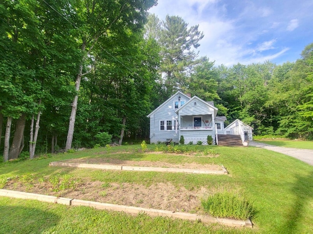 12 Allen St, Wilton, ME 04294 - view of front of house featuring covered porch, a front yard, and a wooded view